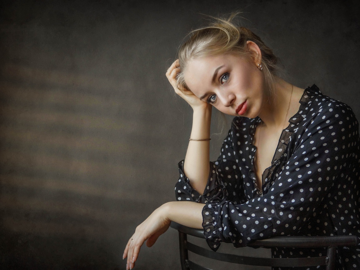Нежная девушка блондинка сидит на стуле