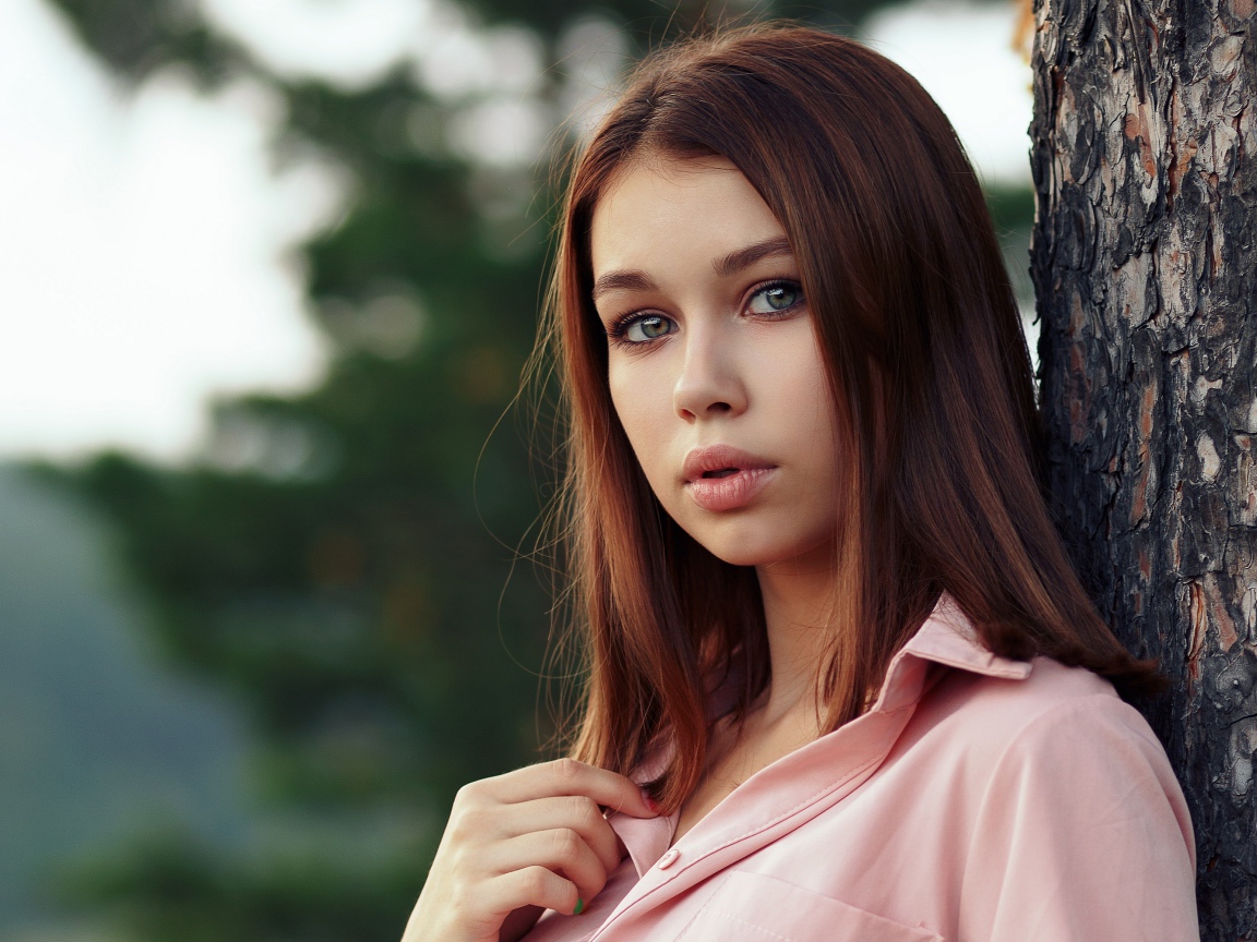 Нежная девушка стоит у дерева