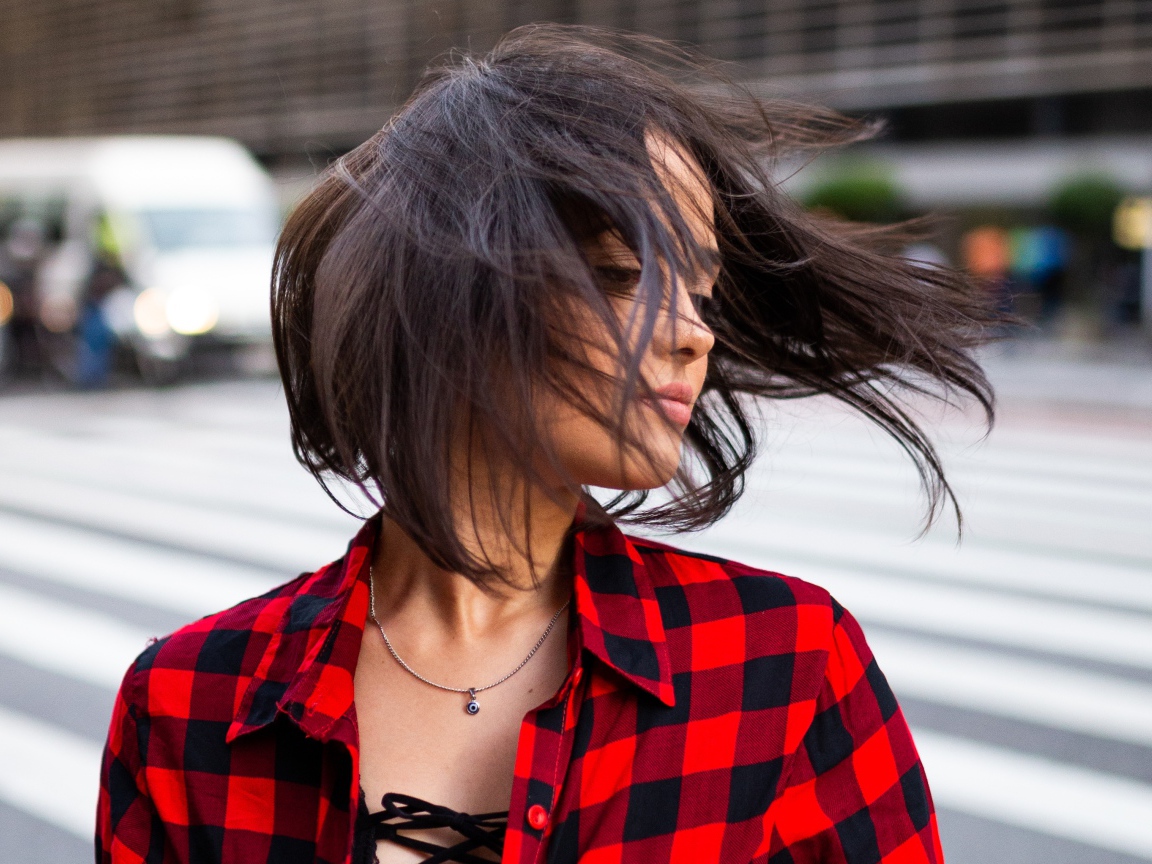 Ветер развивает волосы красивой шатенки в клетчатой рубашке