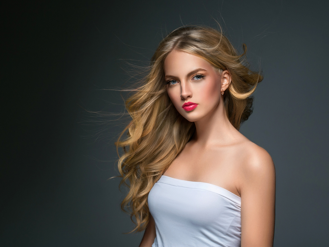 Молодая красивая голубоглазая блондинка на сером фоне