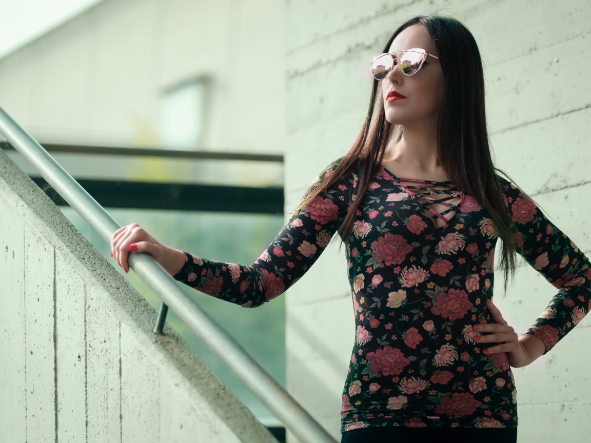 Молодая девушка в солнечных очках стоит на ступеньках