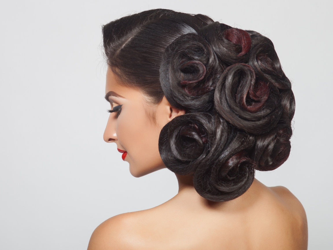 Молодая девушка с красивой прической на сером фоне