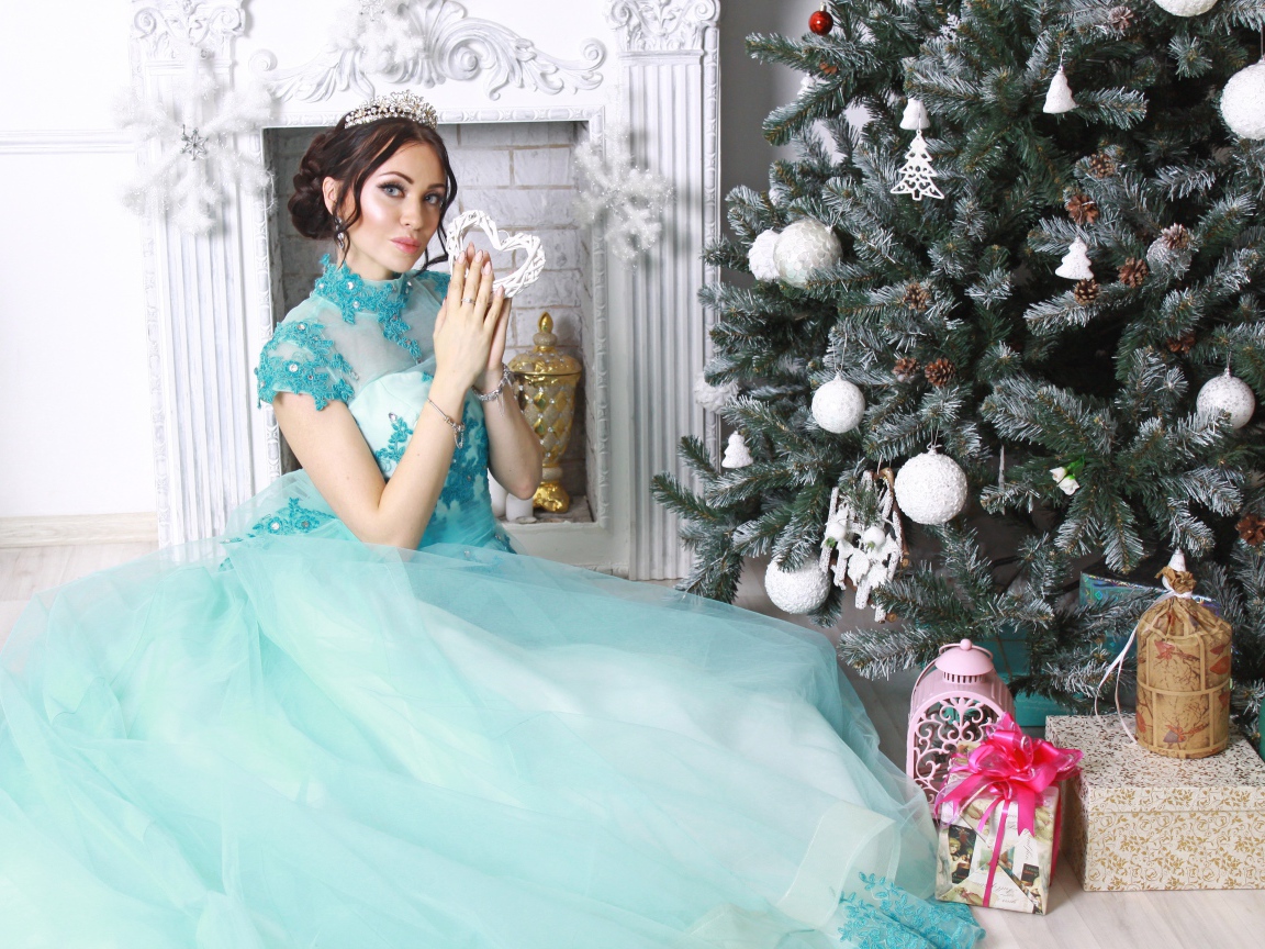 Молодая девушка в красивом голубом платье у новогодней елки