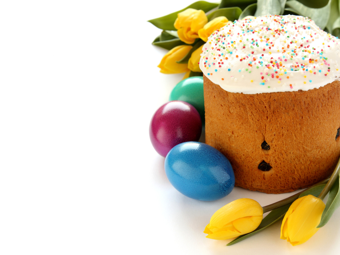 Красивый праздничный кулич с желтыми тюльпанами и крашеными яйцами на белом фоне к Пасхе