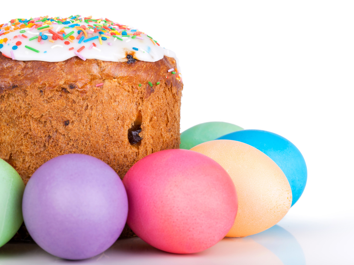 Пасхальный кулич с изюмом на белом фоне с крашеными яйцами 