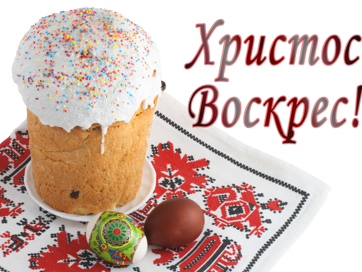 Пасхальный кулич с белой глазурью и крашеными яйцами на рушнике с надписью Христос Воскрес на белом фоне