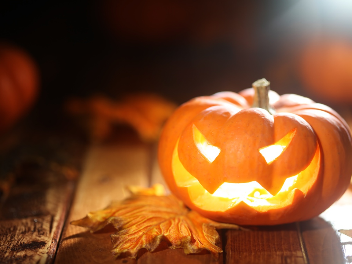 Светящаяся тыква на столе на Хэллоуин