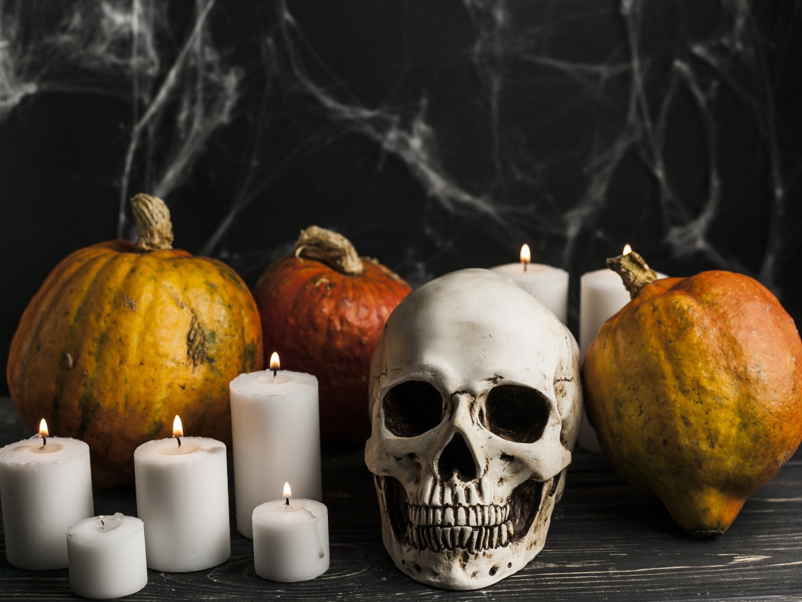 Череп, свечи и тыквы на столе с паутиной