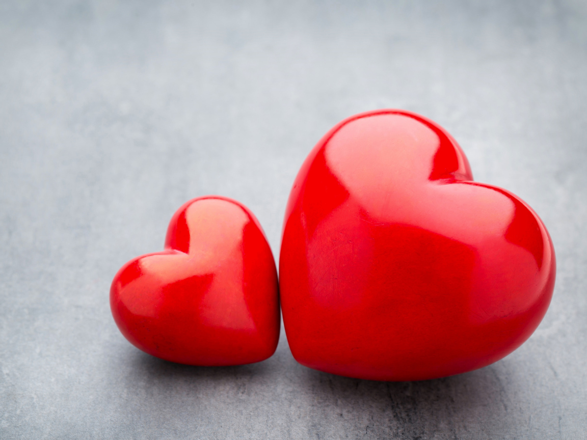 Большое и маленькое красное сердце на сером столе