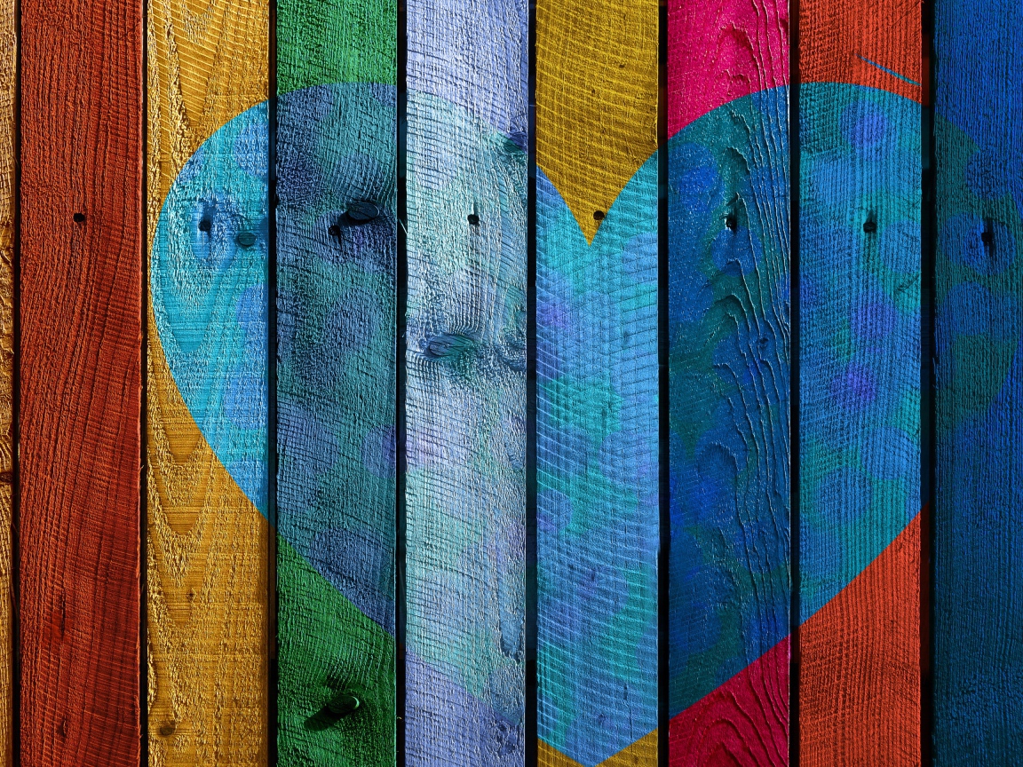 Голубое сердце нарисовано на разноцветном заборе