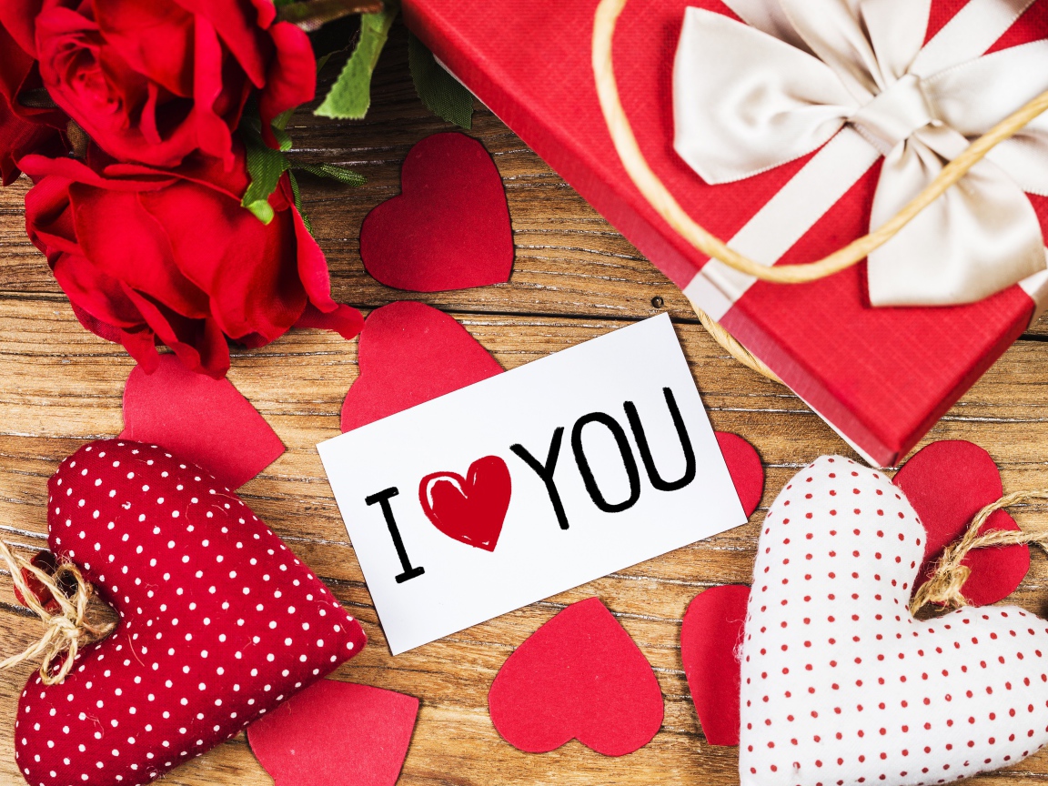 Сердечки, цветы и подарок на столе с запиской