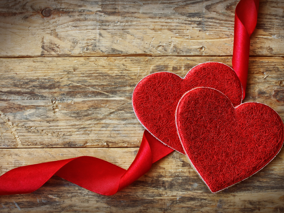 Два сердца с красной лентой на деревянном столе