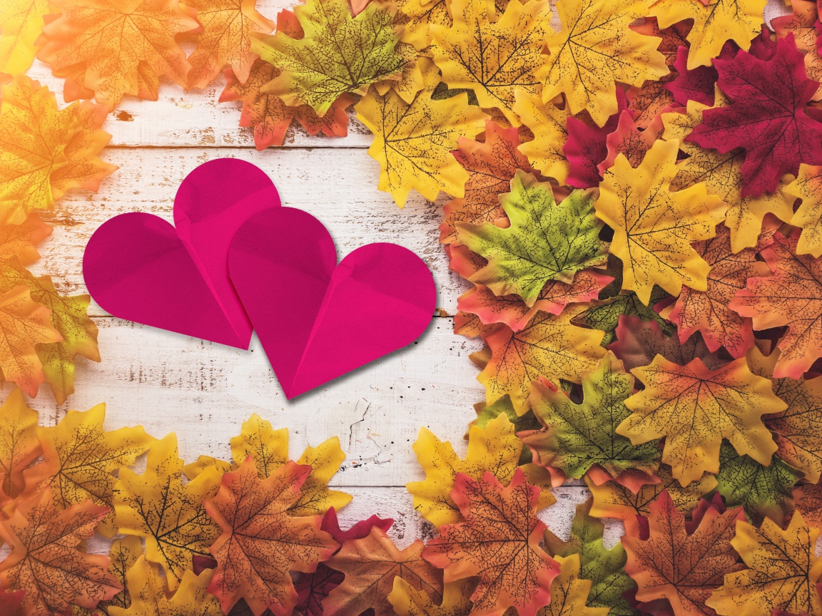 Два красных сердца на столе с желтыми листьями