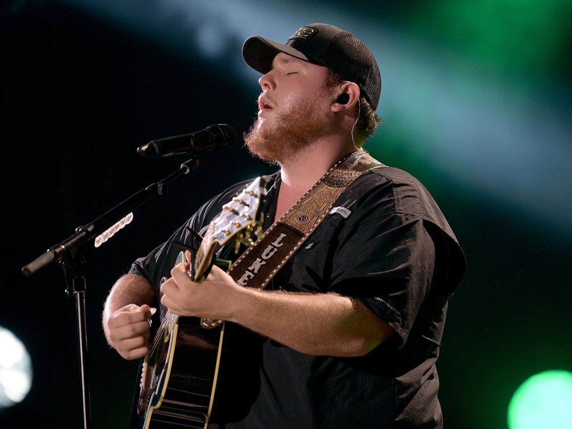 Кантри исполнитель Люк Комбс с гитарой поет на сцене