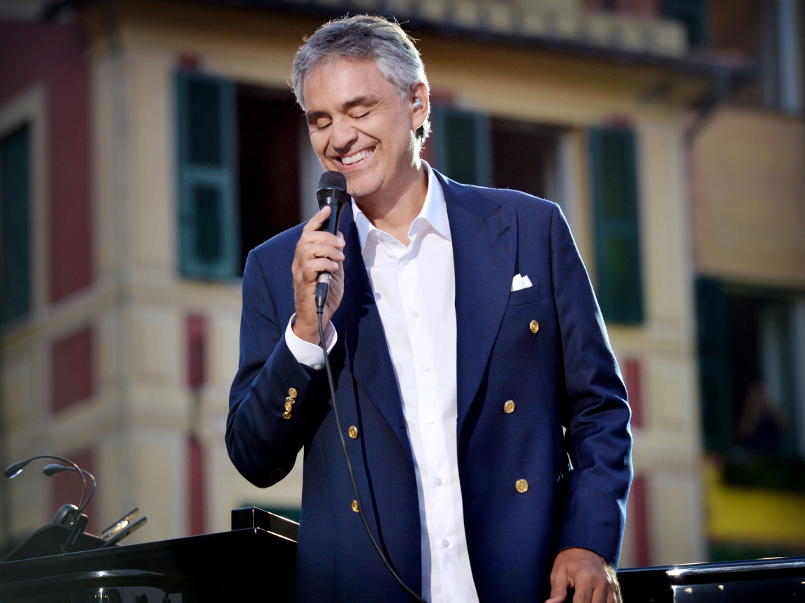 Итальянский певец Андреа Бочелли в костюме с микрофоном