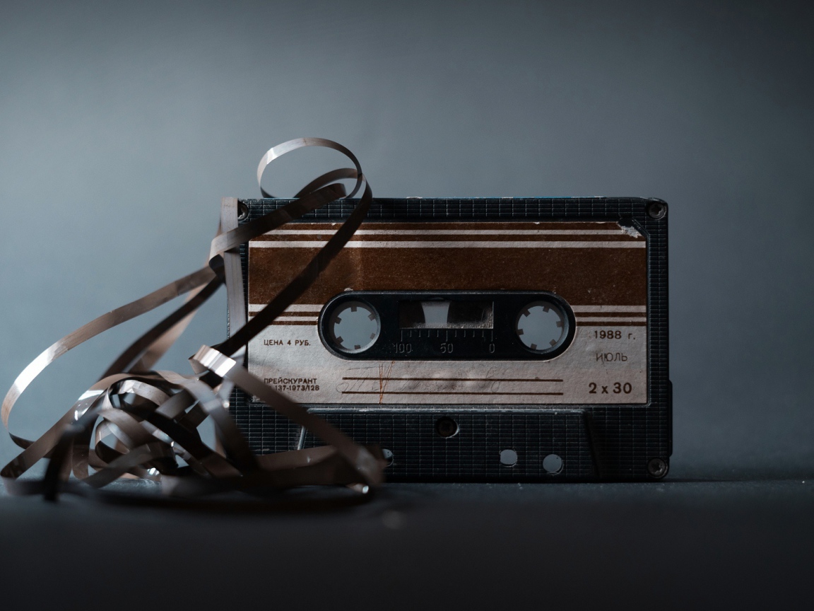 Старая кассета с вытянутой пленкой на сером фоне 