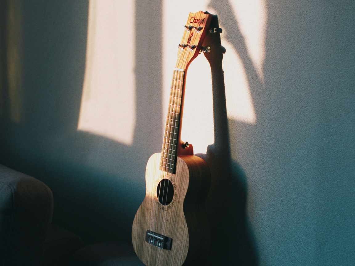 Желтая гитара стоит у серой стены