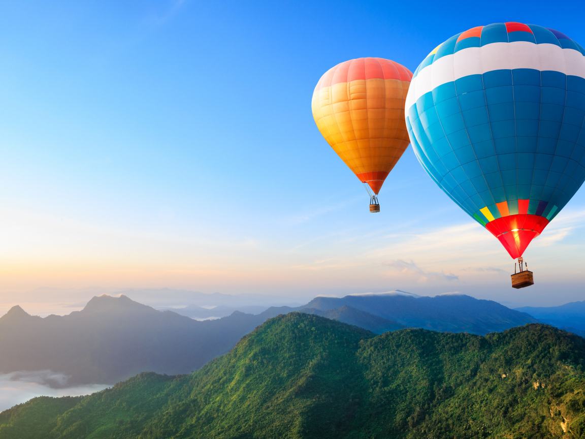 Большие воздушные шары в голубом небе над зелеными холмами