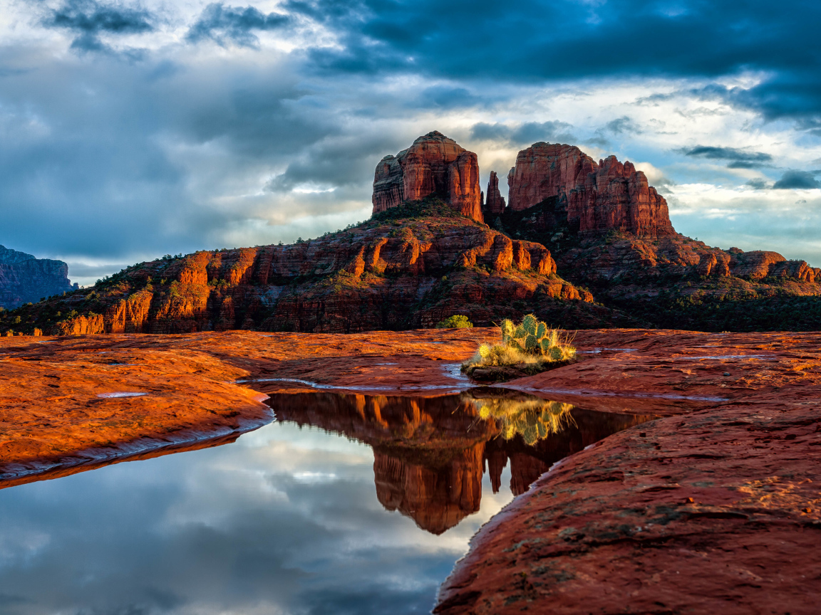 Скалы под пасмурным небом отражаются в воде