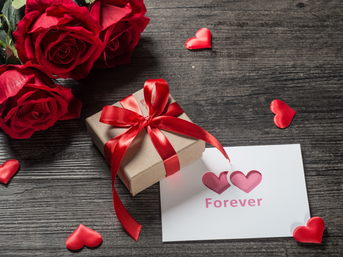 Букет красных роз с подарком и открыткой на столе