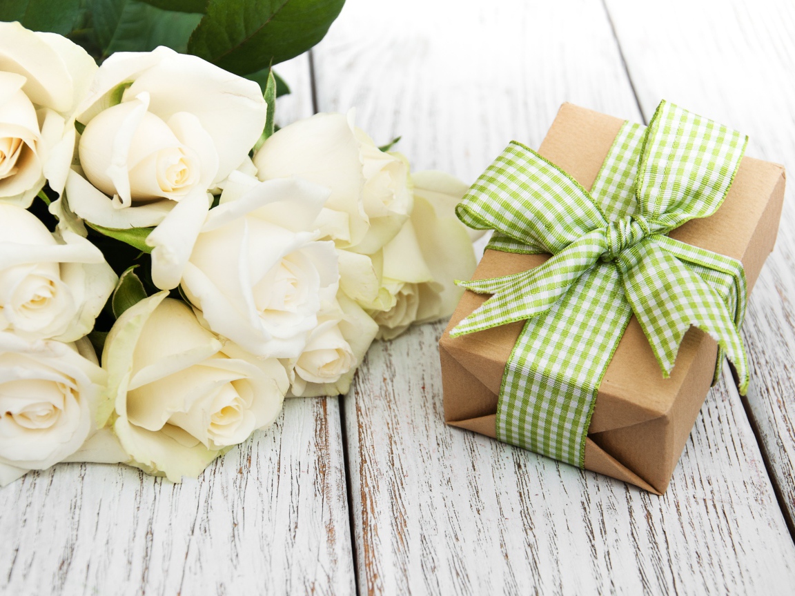 Букет белых роз на столе с подарком