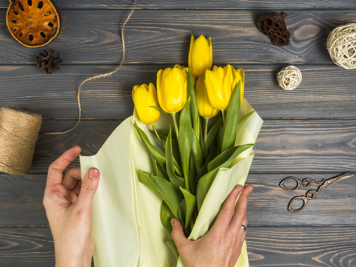 Букет желтых тюльпанов заворачивают в бумагу