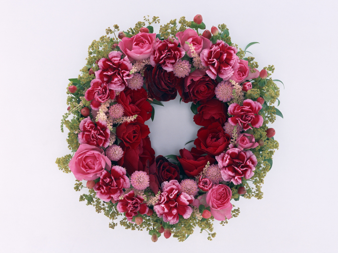 Венок и красных роз с цветами гвоздики на сером фоне