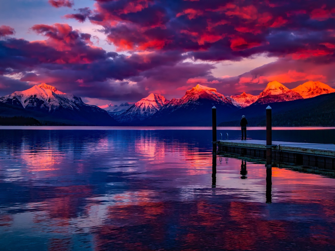 Красивый закат в небе над вершинами заснеженных гор у озера