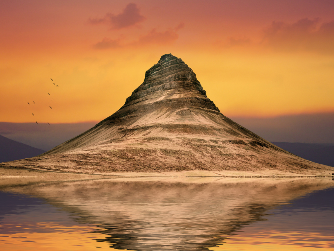 Гора отражается в воде на фоне неба на закате