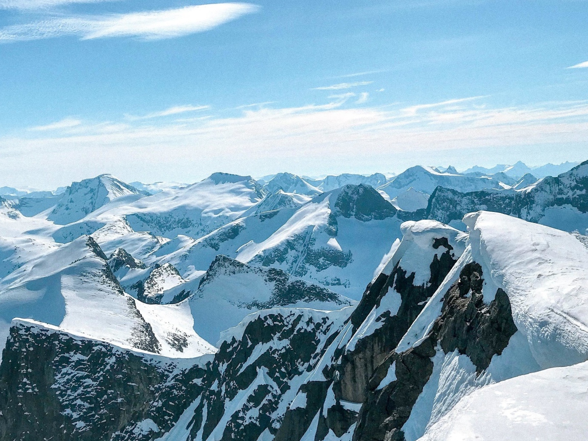 Верхушки заснеженных гор в лучах солнца под голубым небом 