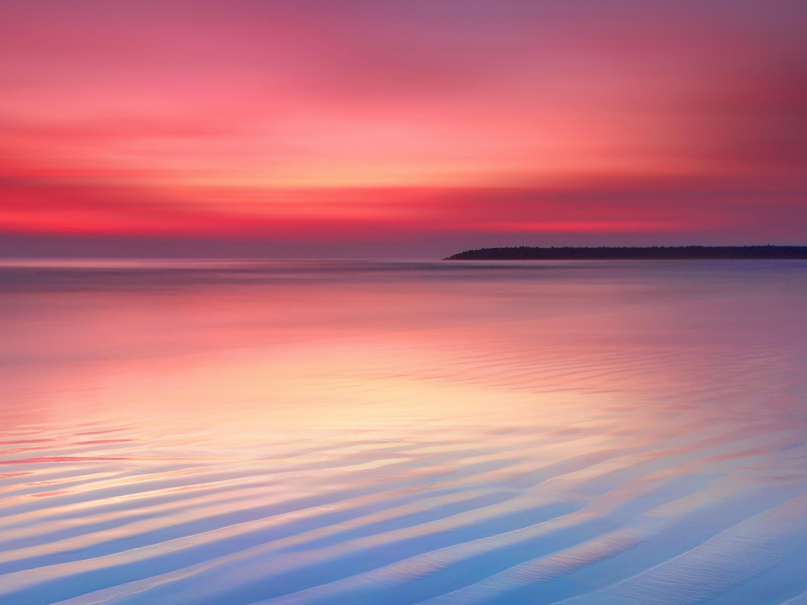 Мокрый белый песок на берегу океана на закате