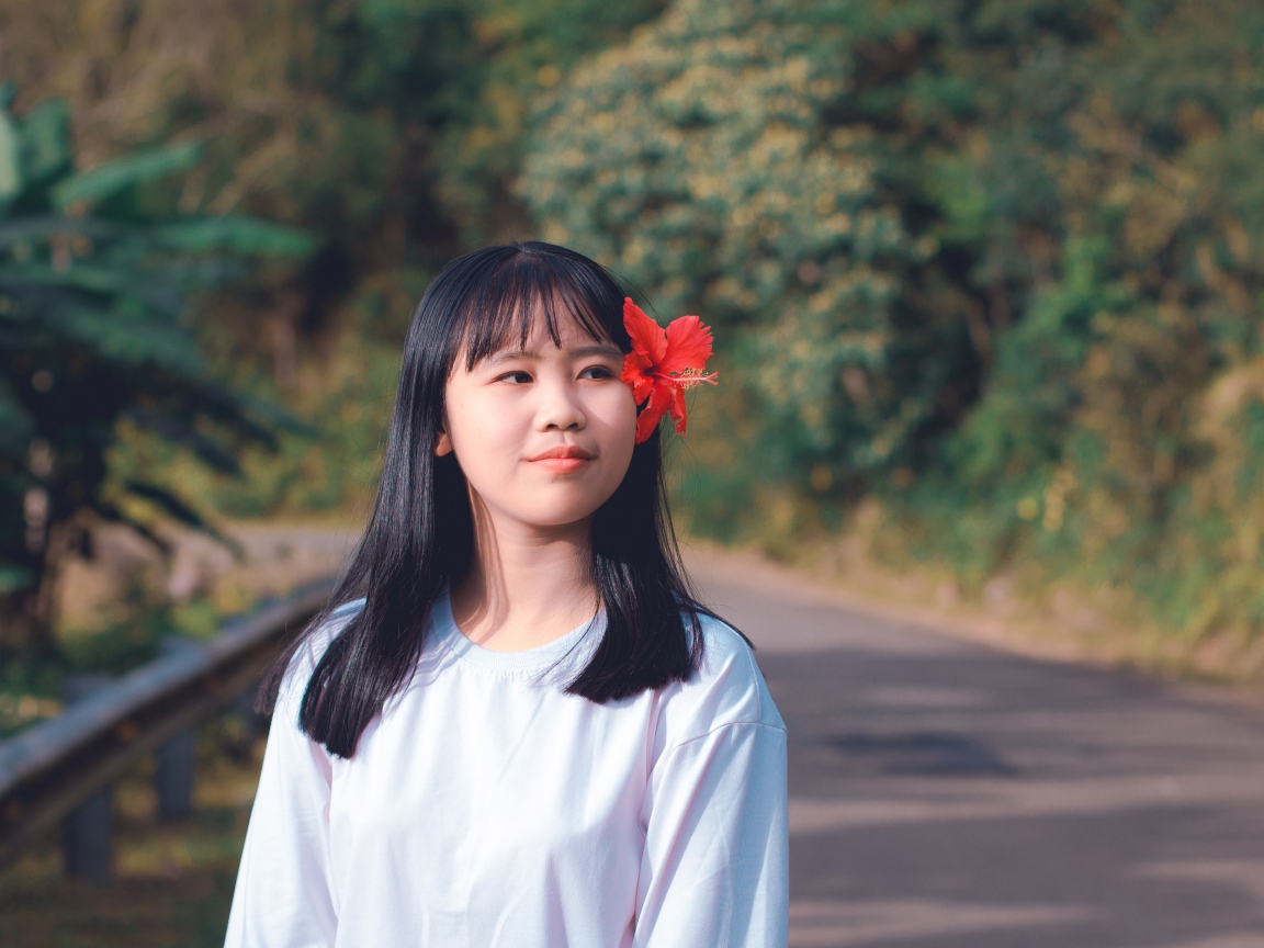 Девушка азиатка с красным цветком гибискуса в волосах