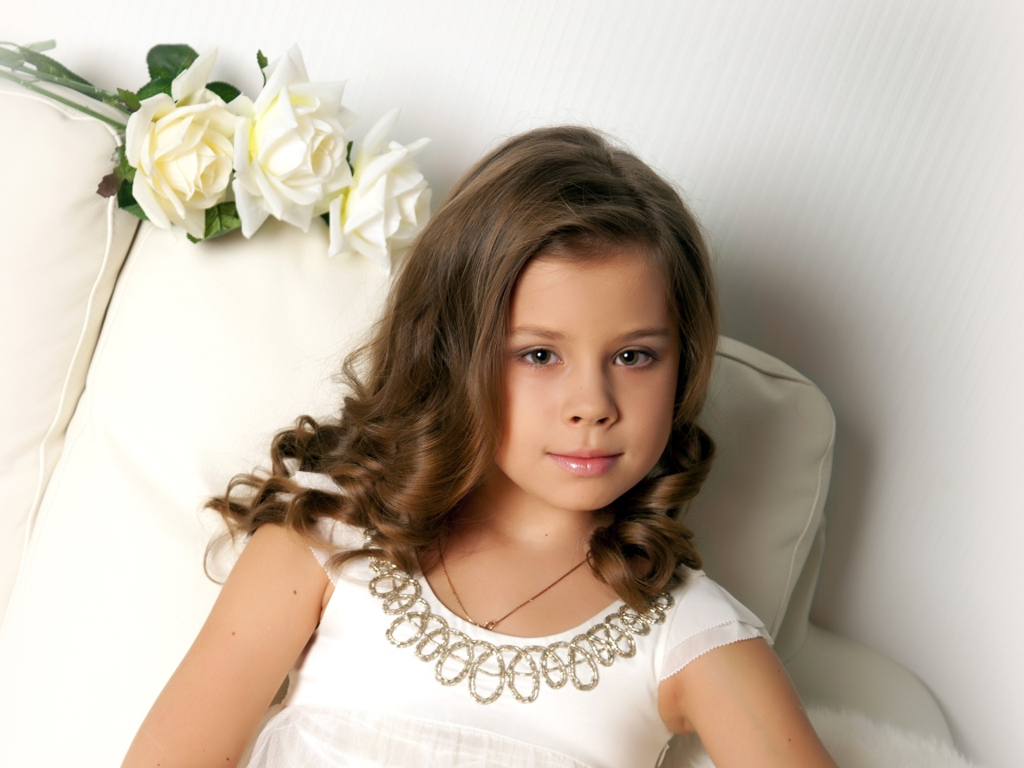 Красивая маленькая девочка сидит в кресле