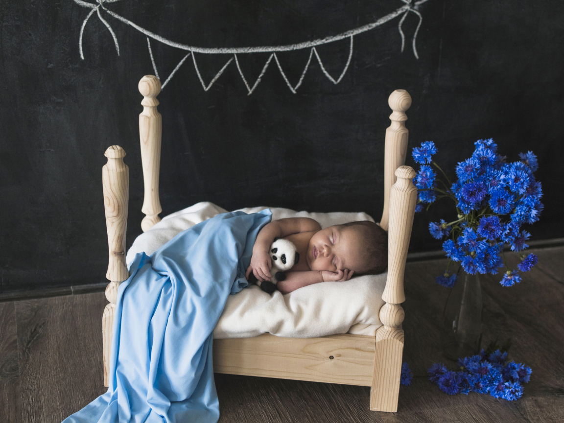 Маленький ребенок спит в деревянной кровати 