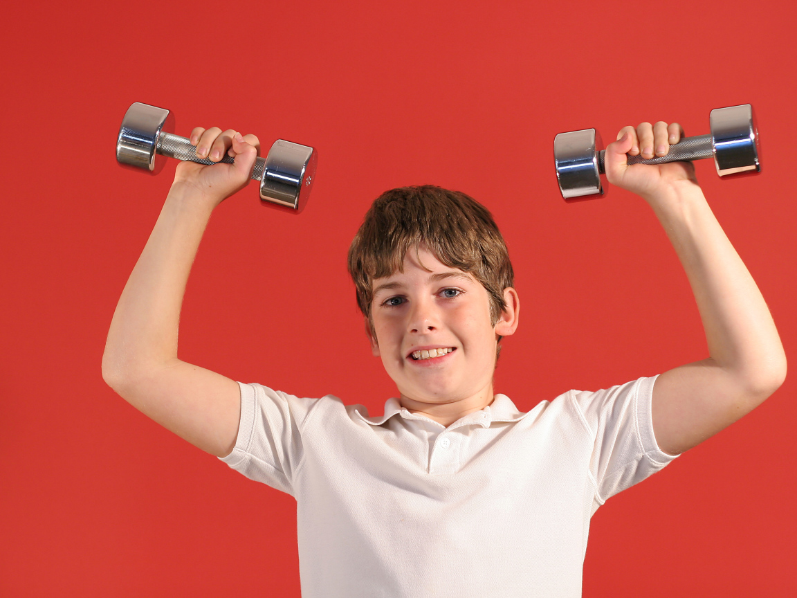 Маленький мальчик с гантелями на красном фоне