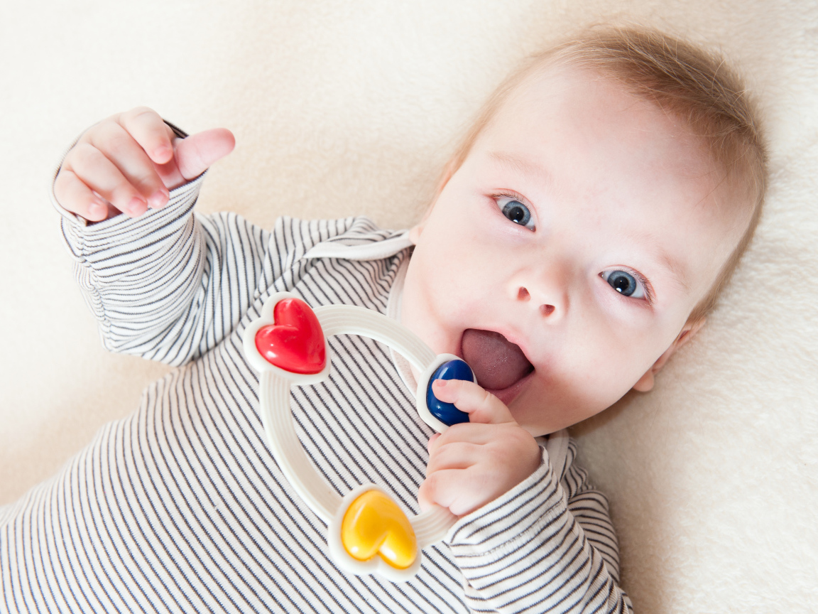 Маленький забавный голубоглазый ребенок с погремушкой