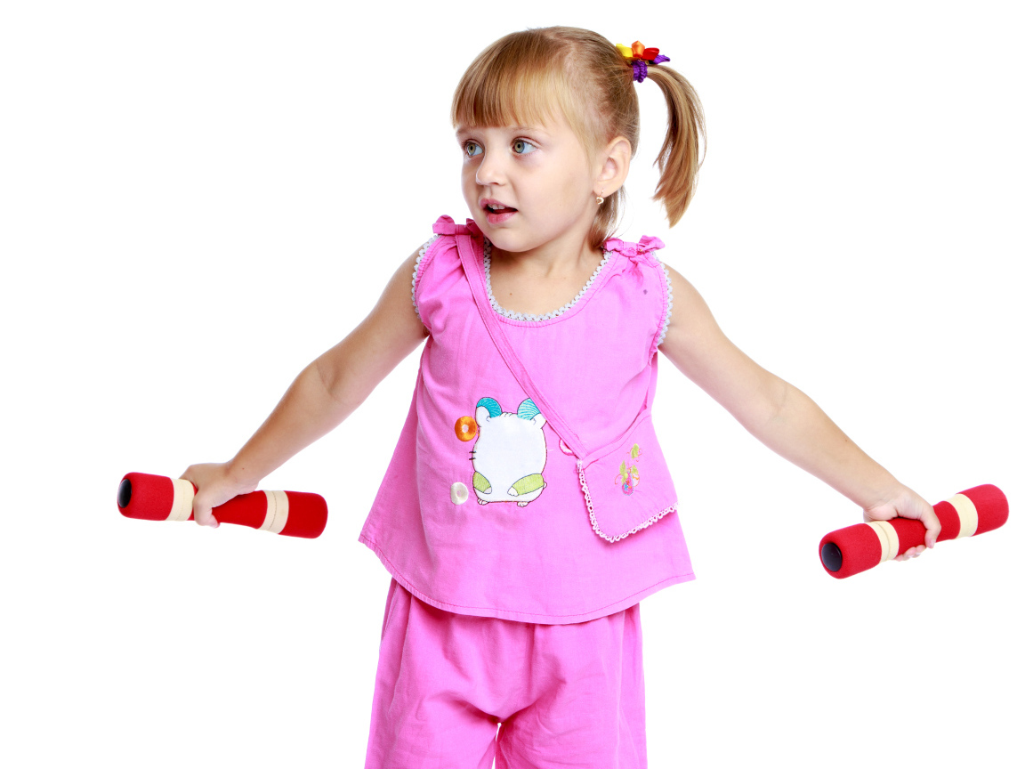 Маленькая девочка в розовом костюме с гантелями в руках на белом фоне