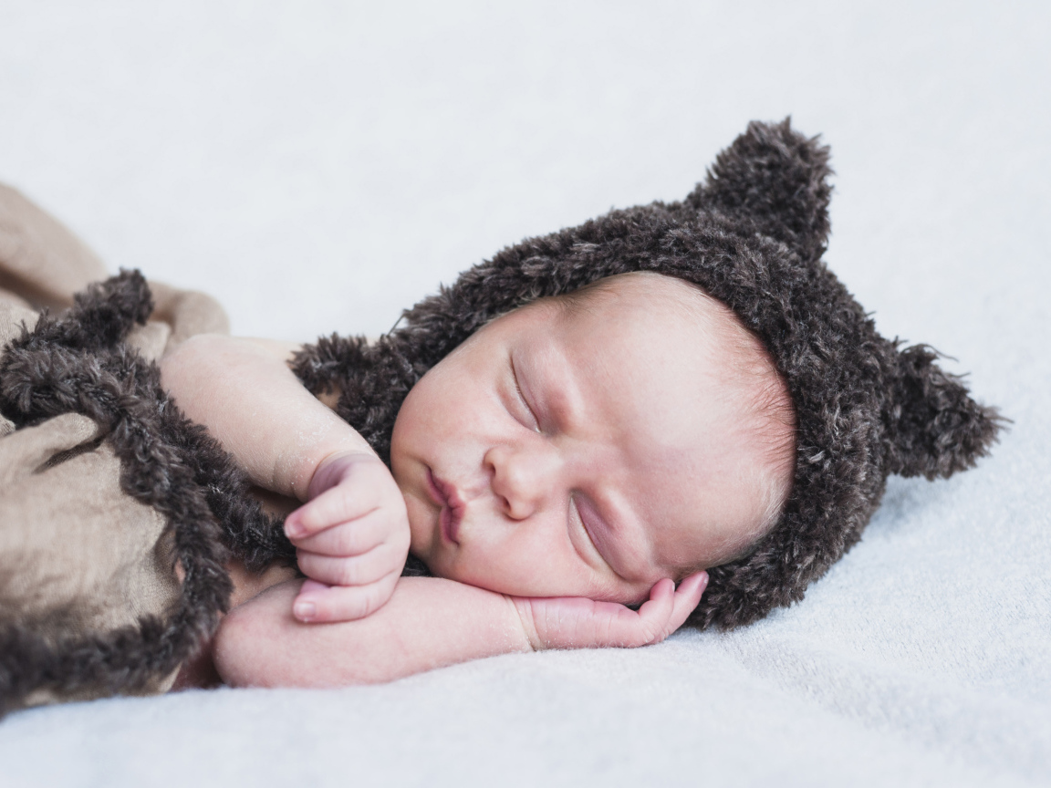 Спящий грудной ребенок в меховой шапке