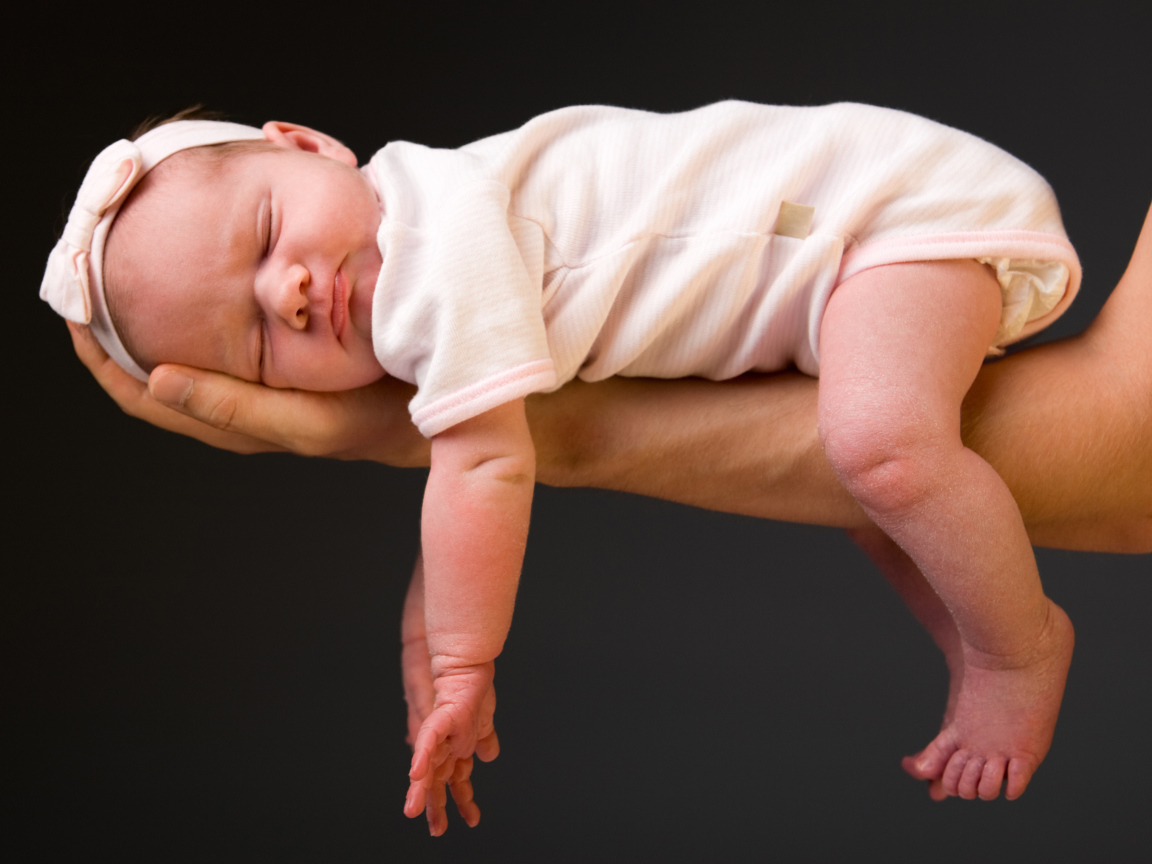 Спящий ребенок на руке у папы на сером фоне