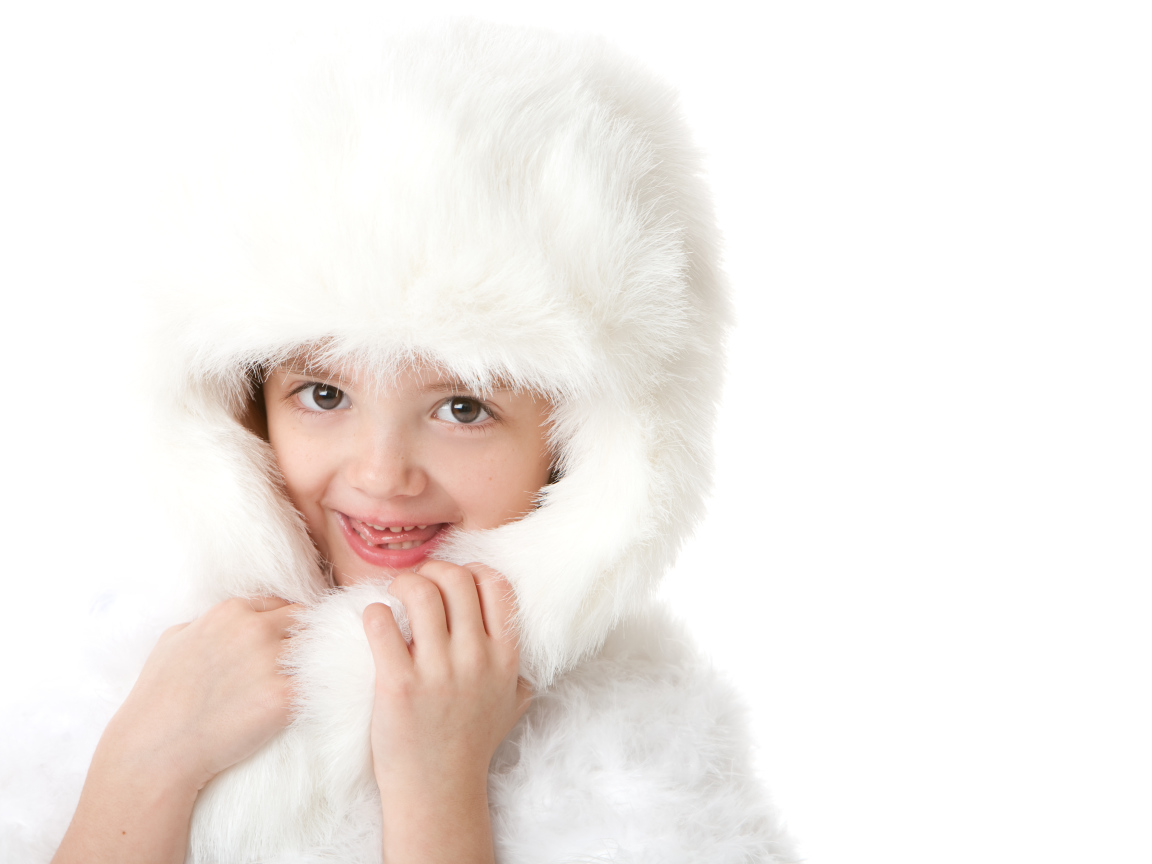 Улыбающаяся маленькая девочка в белой меховой шапке