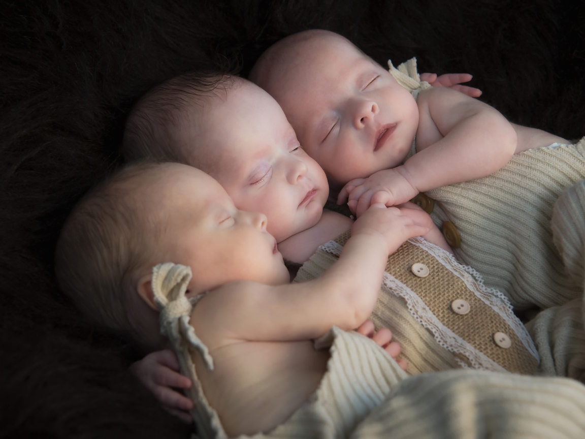 Три маленьких грудных ребенка спят обнявшись 