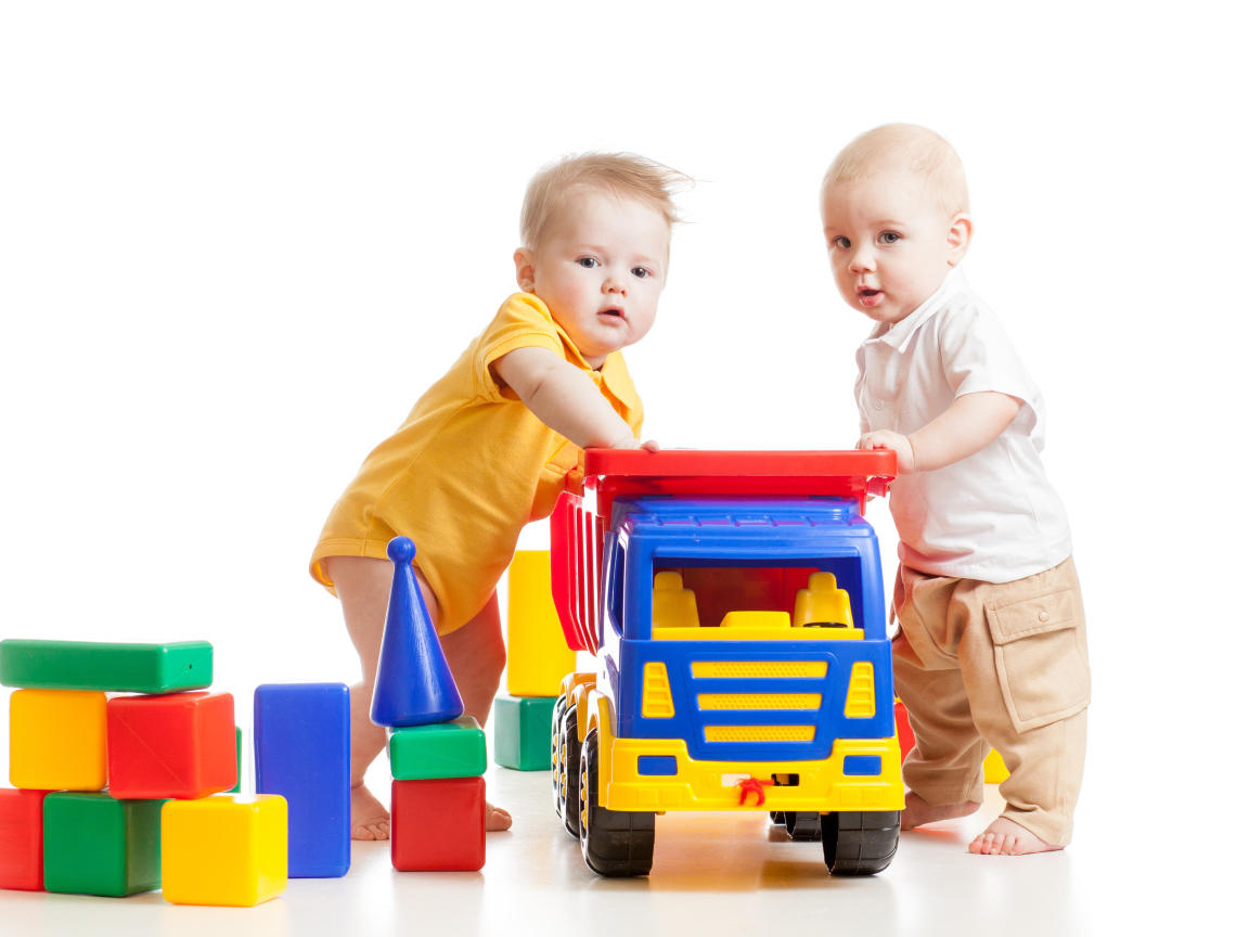 Два маленьких ребенка с игрушками на белом фоне