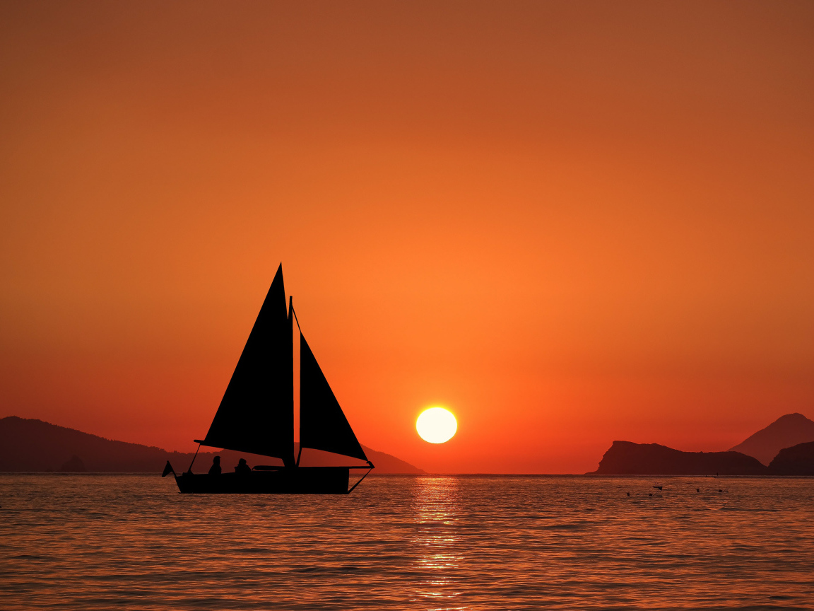 Парусная лодка в море на закате солнца