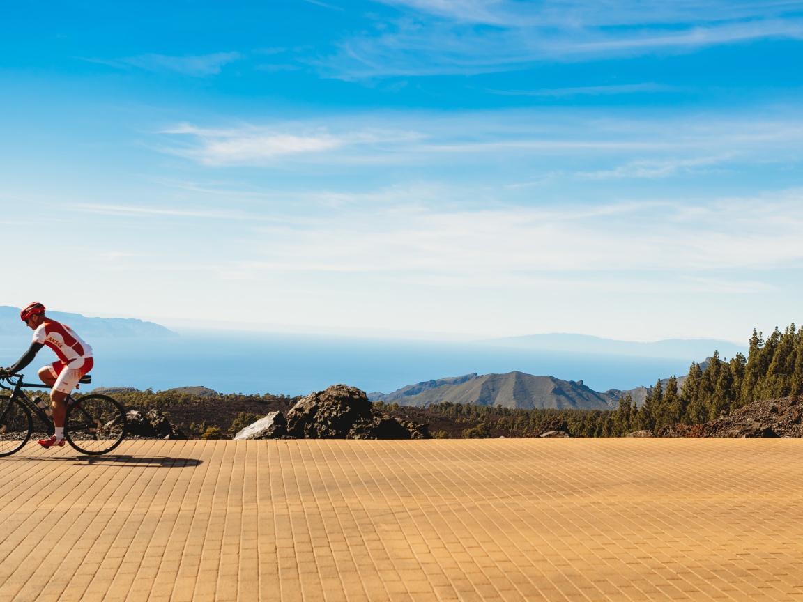 Велосипедист едет по дороге на фоне голубого неба