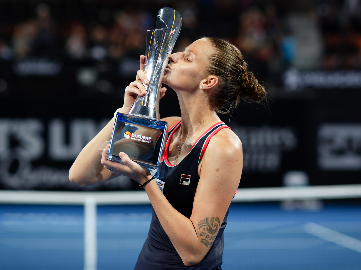 Чешская теннисистка Каролина Плишкова целует кубок на корте