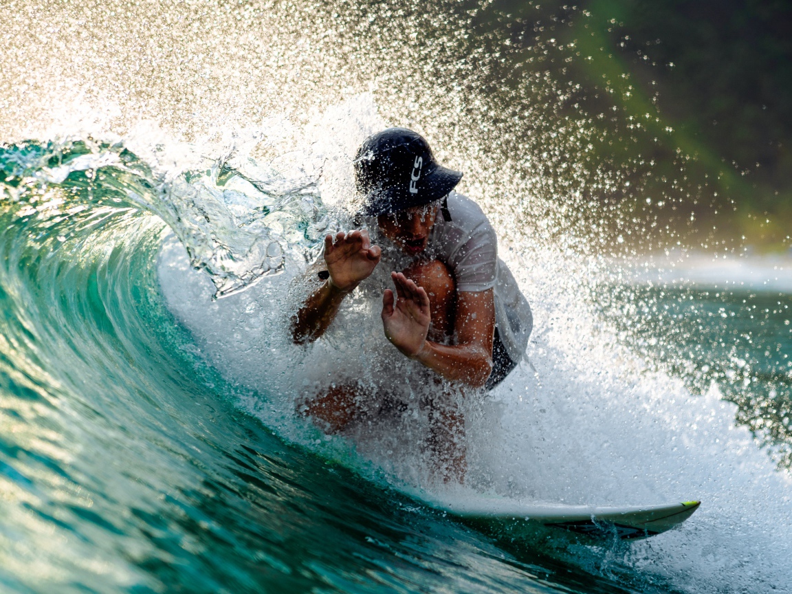 Парень серфингист ловит голубую морскую волну