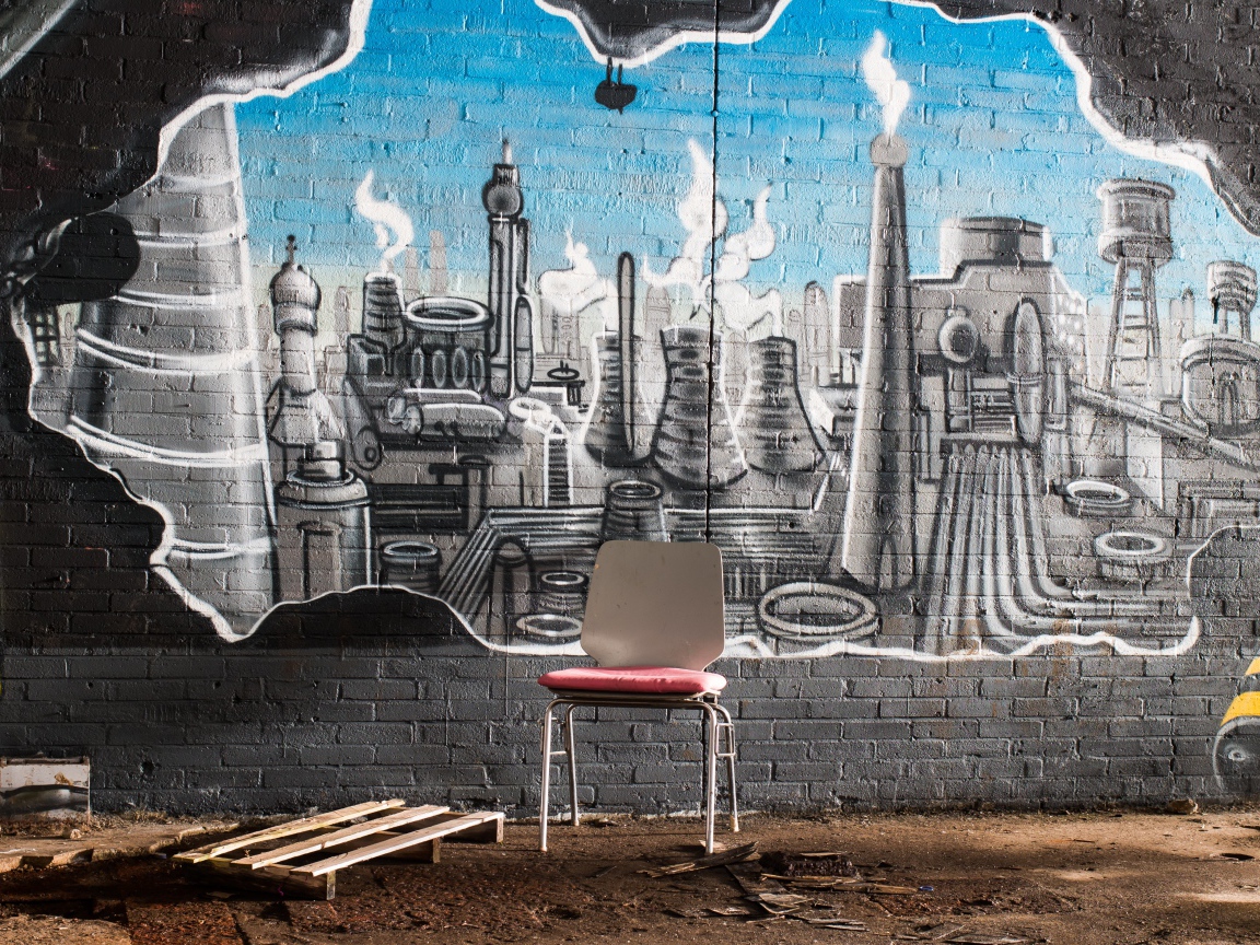 A chair stands by a brick wall with graffiti