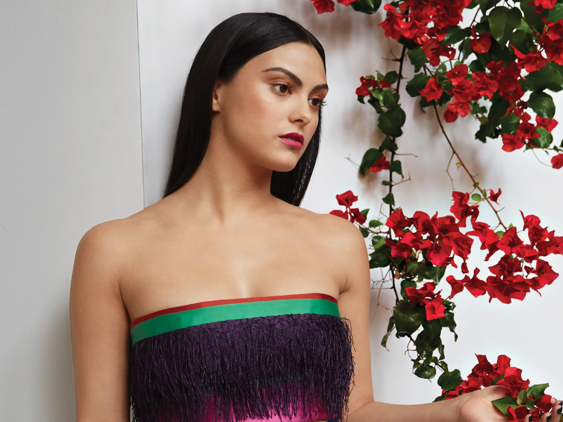 Актриса Камила Мендес стоит у стены с цветами