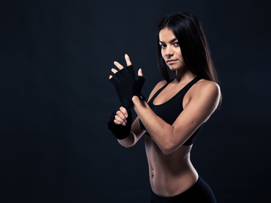 Красивая спортивная девушка в перчатках на сером фоне