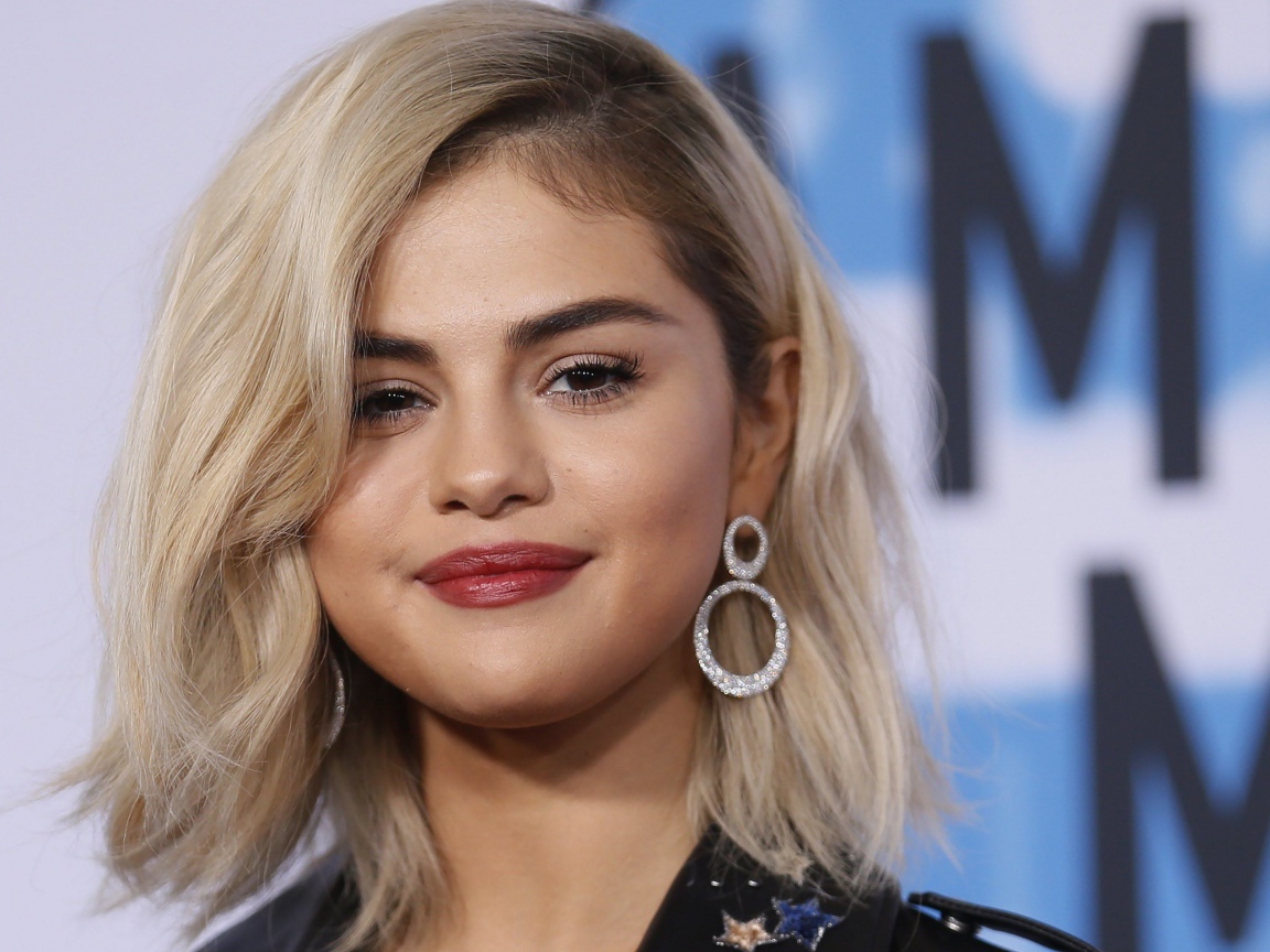 Красивая блондинка, актриса Селена Гомес с серьгами в ушах